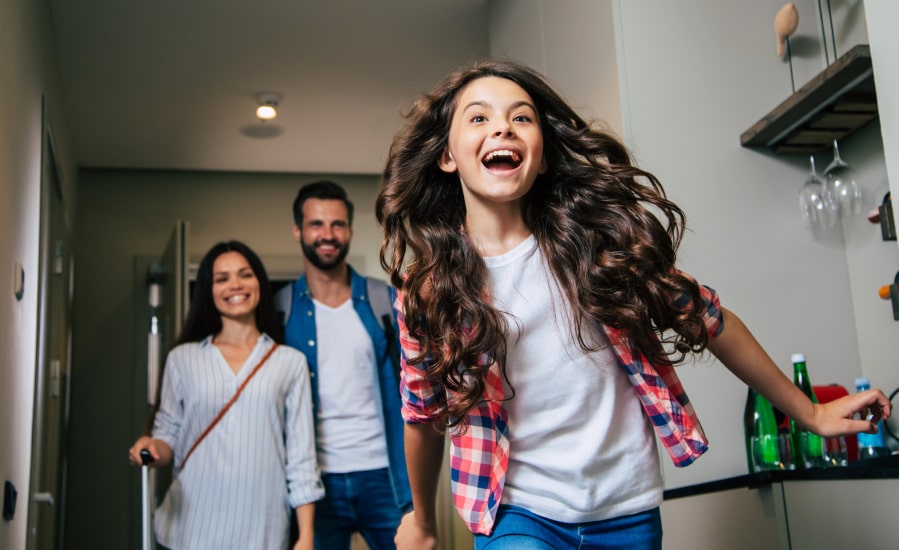 Excited young girl bursting into hotel room with family