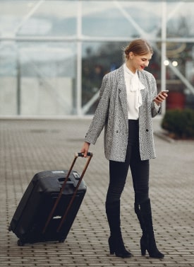 Woman looking at phone with suitcase in tow