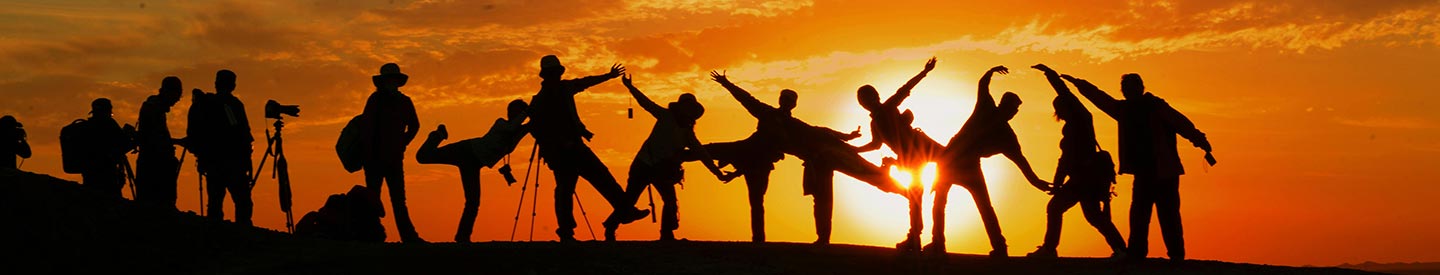 Silhouette of a group of people posing for a picture on a mountain in the sunset